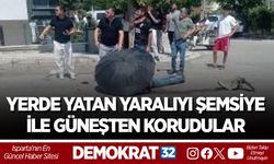 YERDE YATAN YARALIYI ŞEMSİYE İLE GÜNEŞTEN KORUDULAR