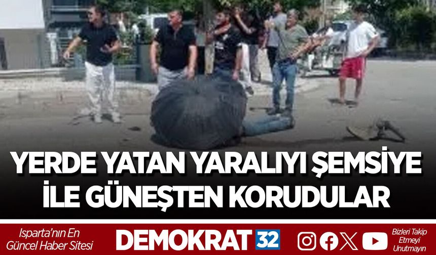 YERDE YATAN YARALIYI ŞEMSİYE İLE GÜNEŞTEN KORUDULAR